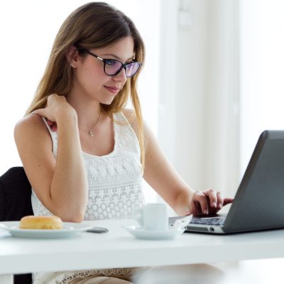Portrait of pretty young woman using her laptop at home.